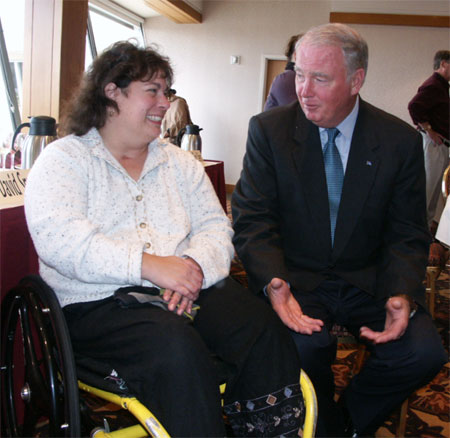 Mona McAleese seated in wheel chair talking to Governor Murkowski